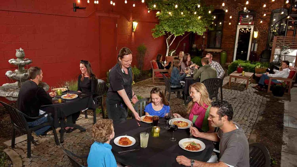 Waitress serving a family at Iozzos Garden Of Italy patio